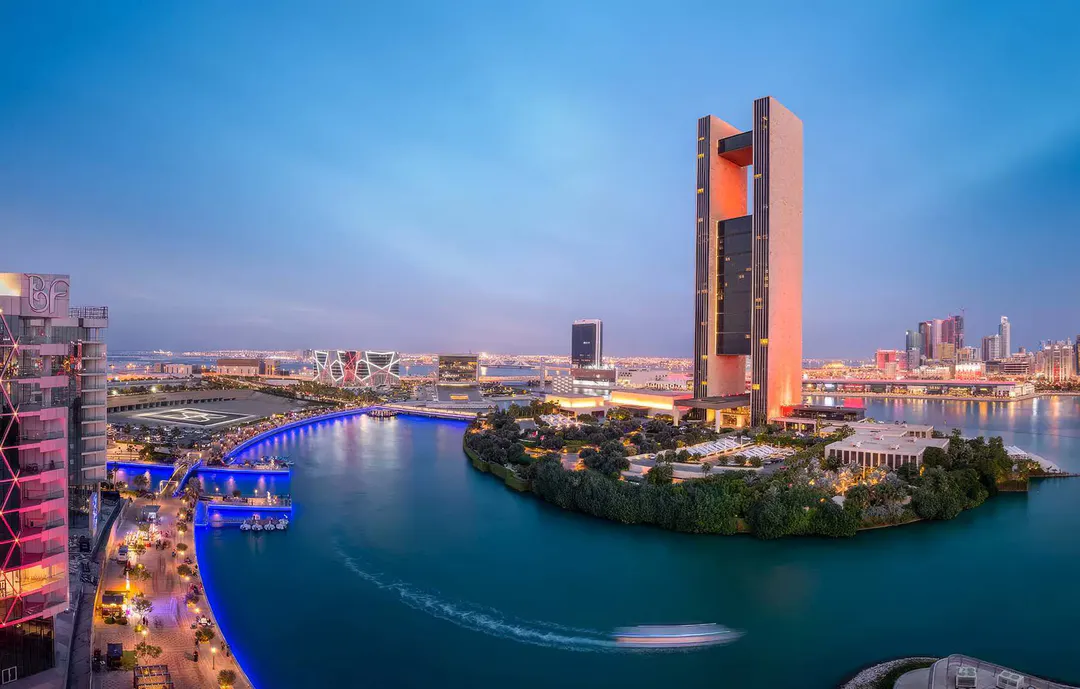 Bahrain Bay in Manama at dusk, with its landmark tower and the illuminated waterfront promenade